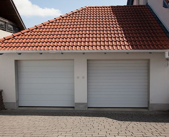a white garage door with a red tile roof