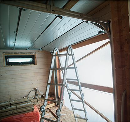 a ladder is sitting in a garage next to a garage door .