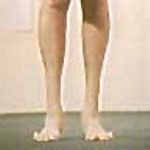 A pair of bare human feet standing on a green surface, showing splayed toes.