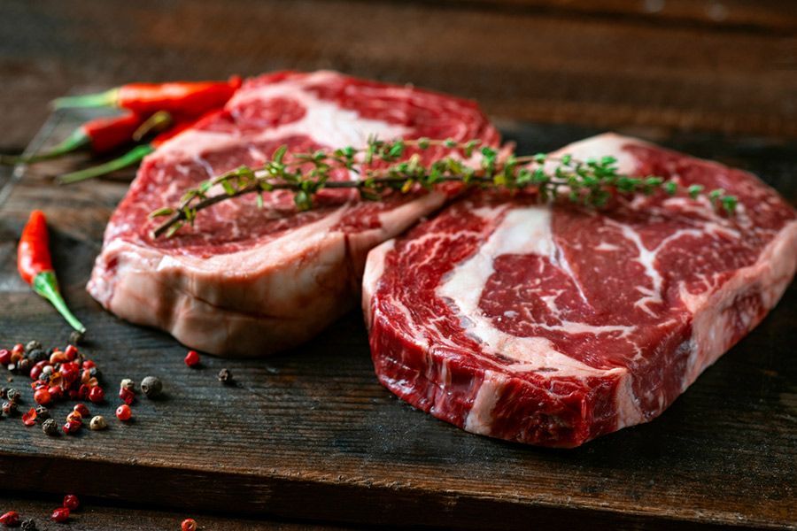 Two Raw Steaks Are Sitting on a Wooden Cutting Board — LZH Butchers in Bungalow, QLD