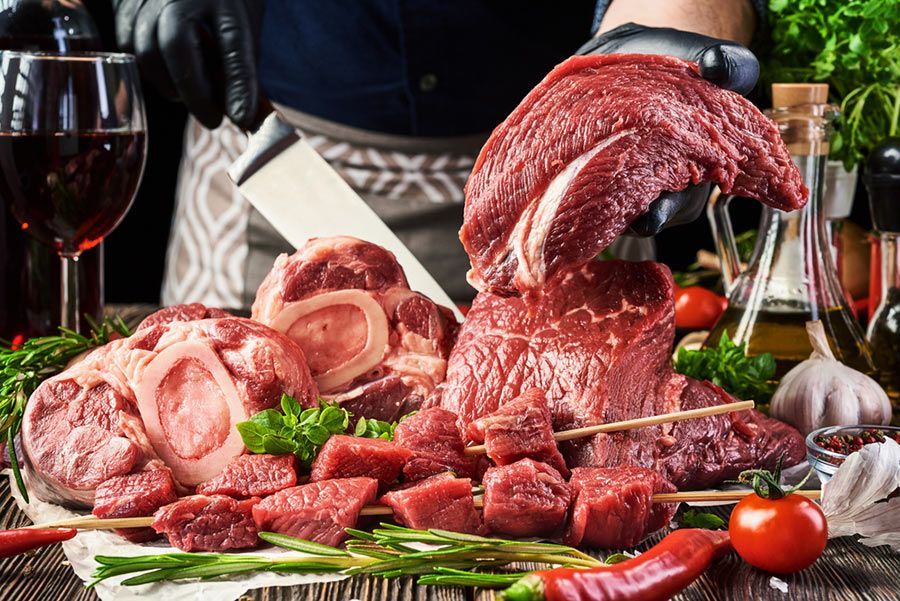 A Man is Cutting a Piece of Raw Beef on a Wooden Table — LZH Butchers in Bungalow, QLD