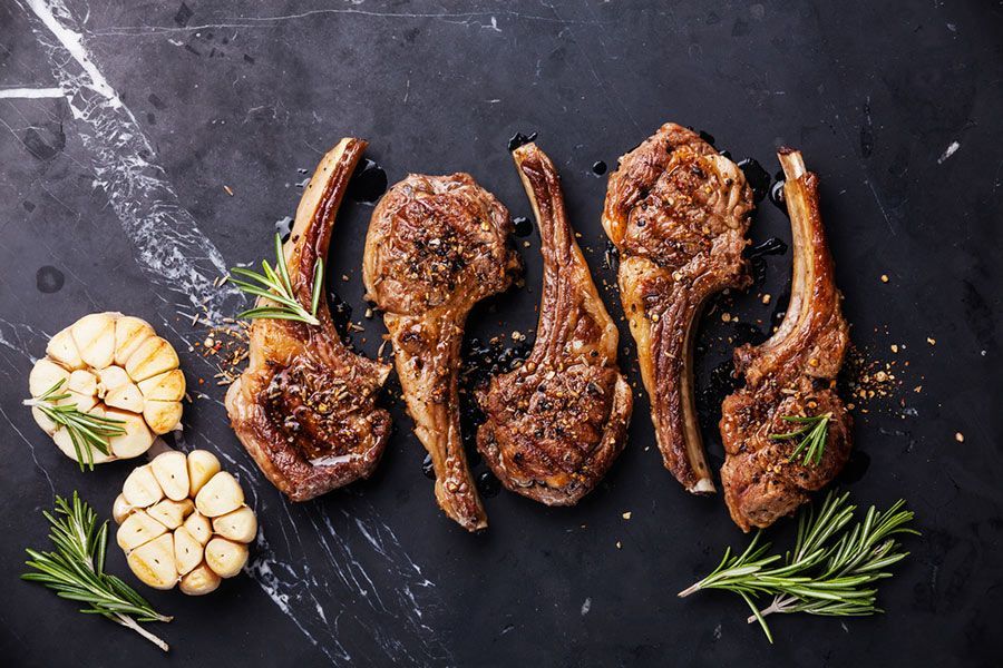 Grilled Lamb Chops With Garlic and Rosemary on a Black Table — LZH Butchers in Bungalow, QLD
