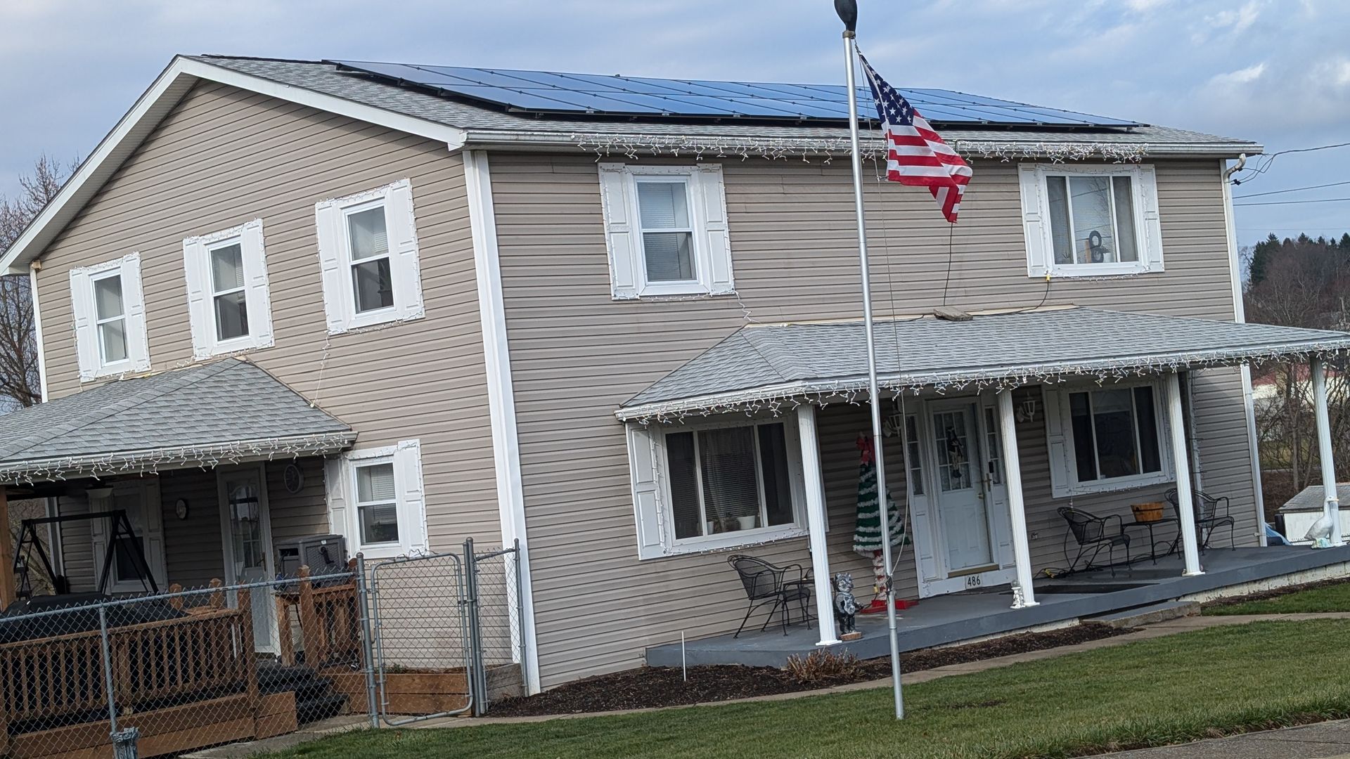 A house with solar panels on the roof and an american flag
