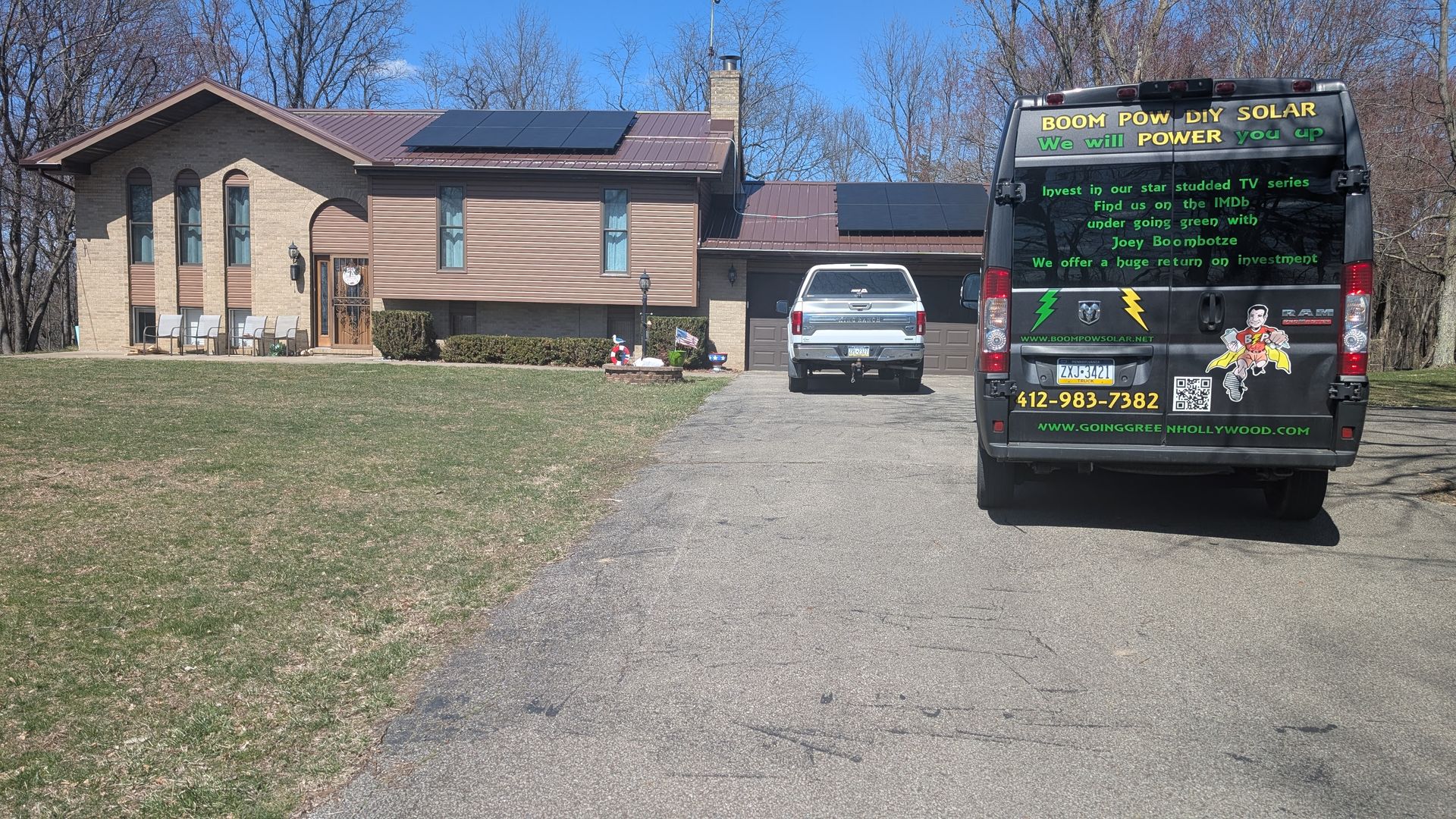 A house with solar panels on the roof, a pickup truck, and a van in the driveway.