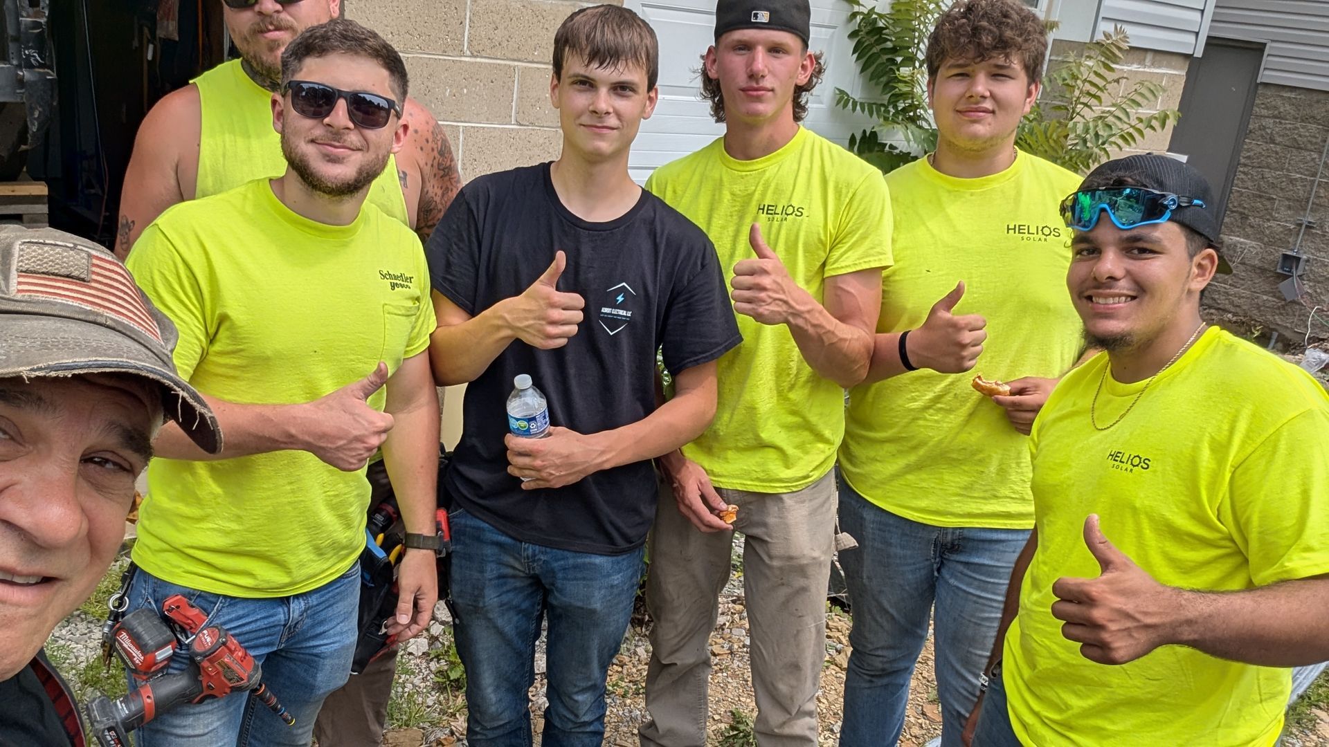 A group of construction workers are posing for a picture and giving a thumbs up.
