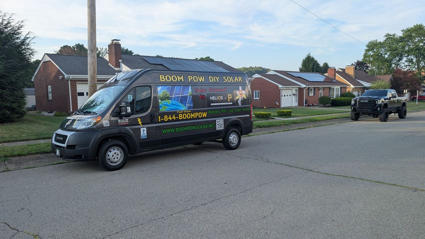 A food truck is parked on the side of the road in front of a brick house.