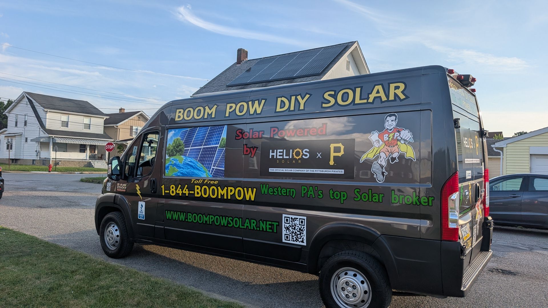A van with solar panels on the roof is parked in front of a house.