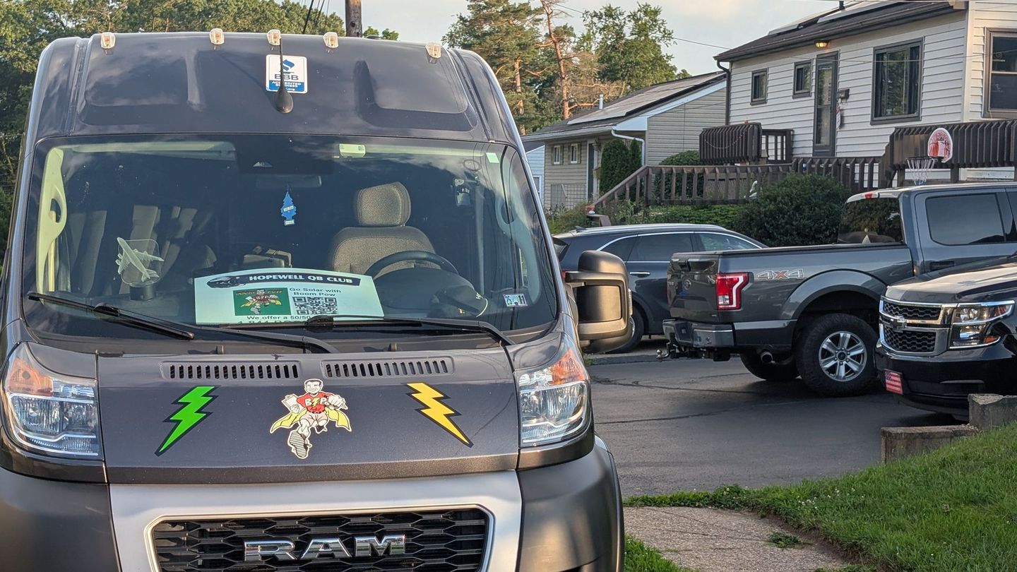 A ram van is parked in a driveway next to a house.