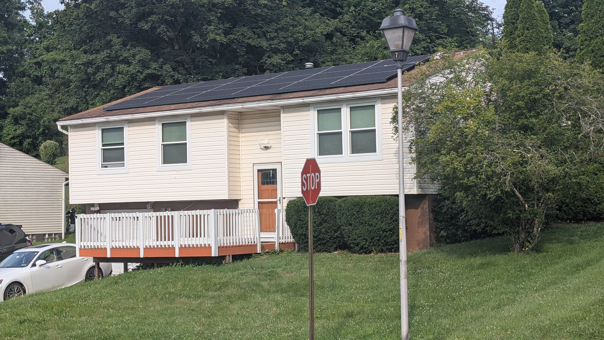 A house with solar panels on the roof and a stop sign in front of it.
