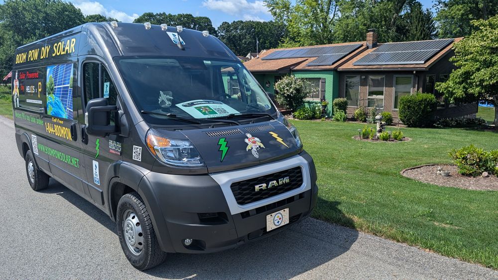 A black van is parked on the side of the road in front of a house.