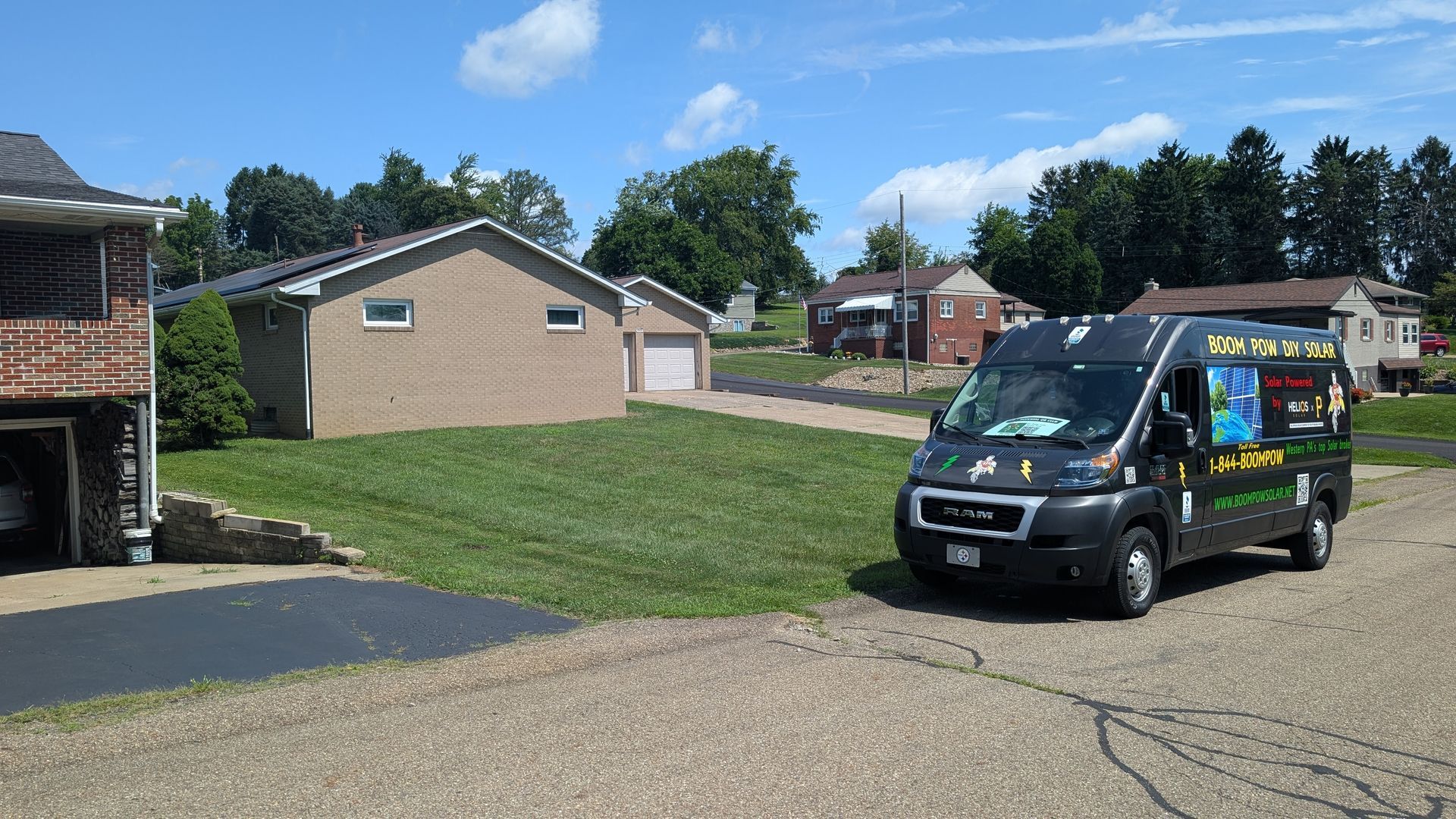 A service van parked on a gravel driveway in a residential area on a sunny day. Houses and green lawns are in the background.