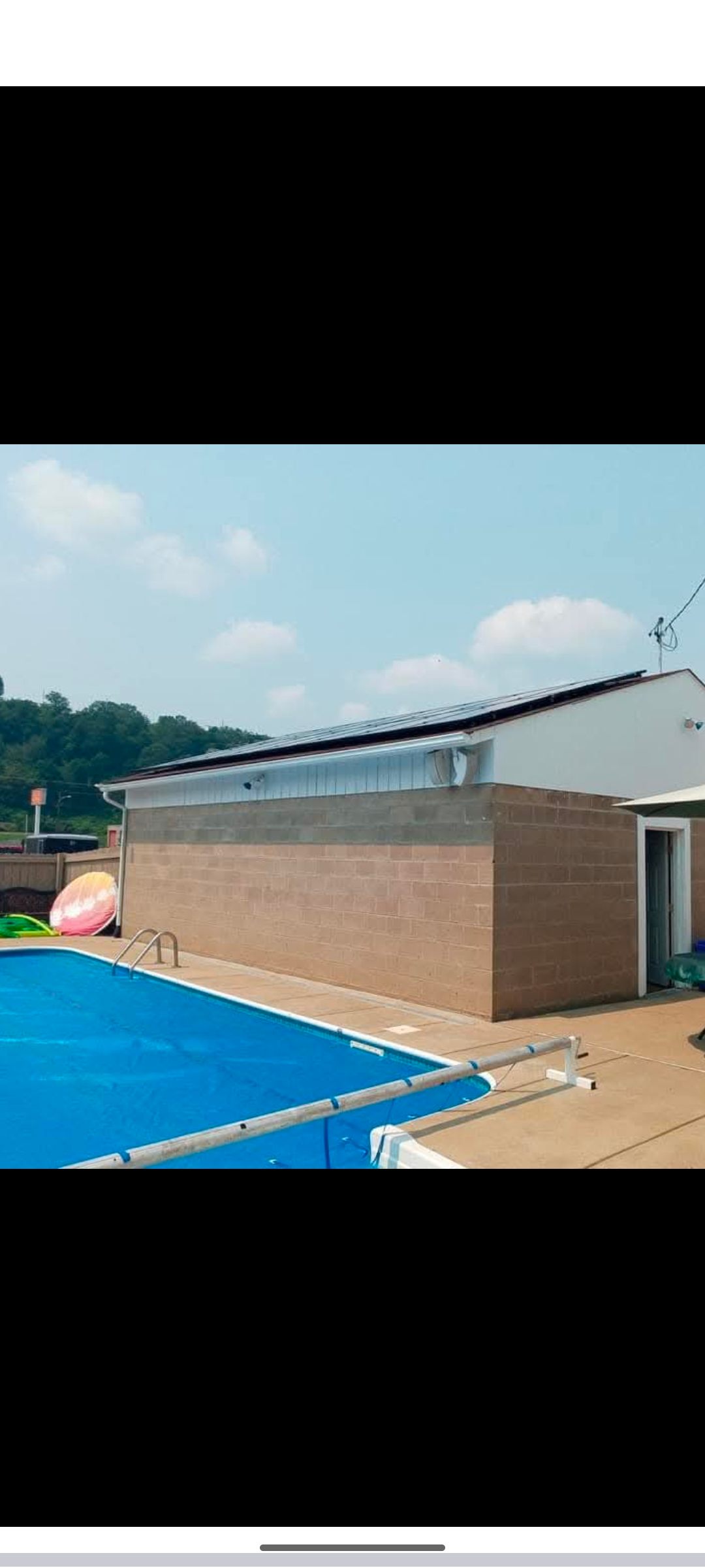 A swimming pool with a blue cover and a building in the background.
