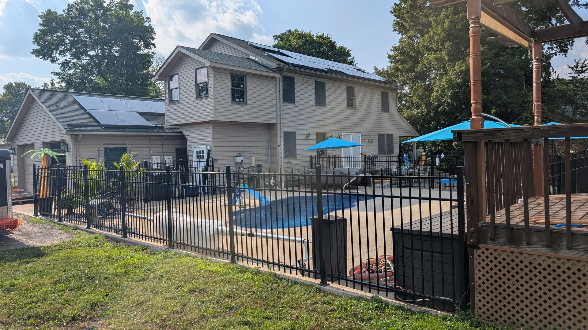 Backyard with a fenced pool and a two-story house with solar panels.