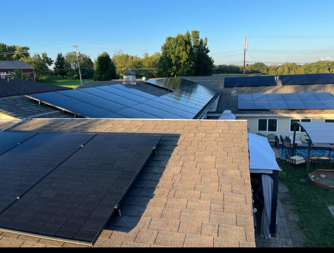 Solar panels installed on multiple house roofs under a blue sky.