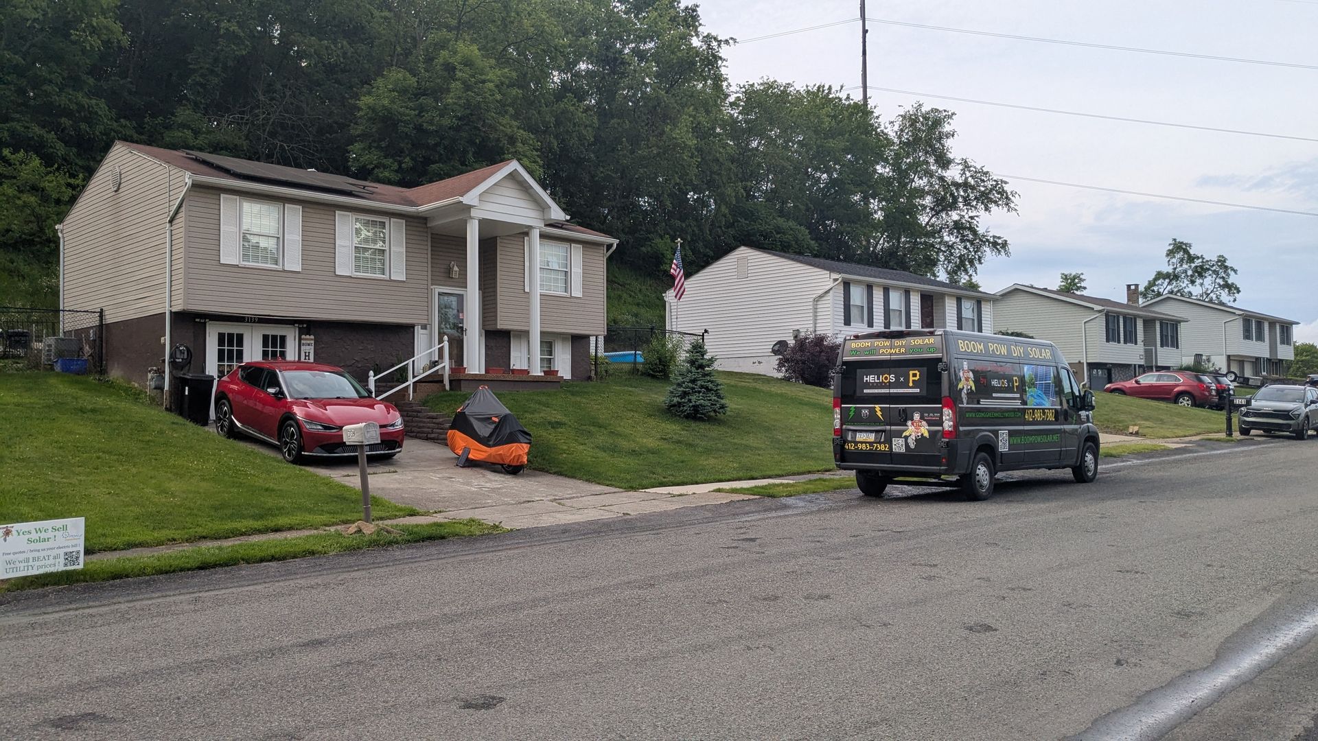 A couple of cars are parked in front of a house.