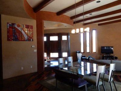Dining room with large glass table, artwork, brown walls, and exposed beams.