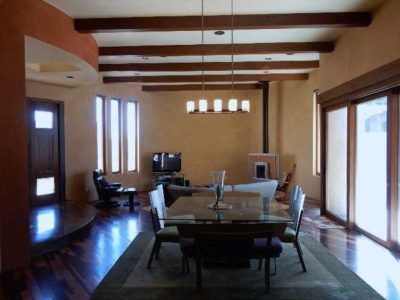 Living room with dark wood floors, exposed beams, and a dining table.