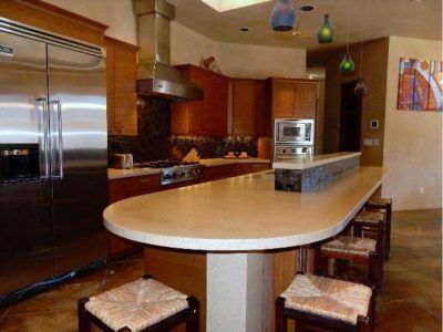 Kitchen with stainless steel appliances, dark wood cabinets, and a curved countertop with stools.