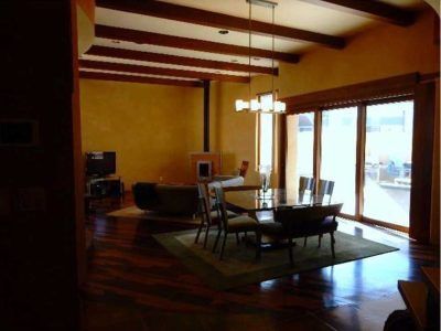 Living room with wood beams, dining table, sliding glass doors, and yellow walls.