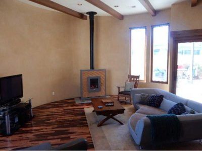 Living room with wood floors, tan walls, fireplace, sofa, and TV.