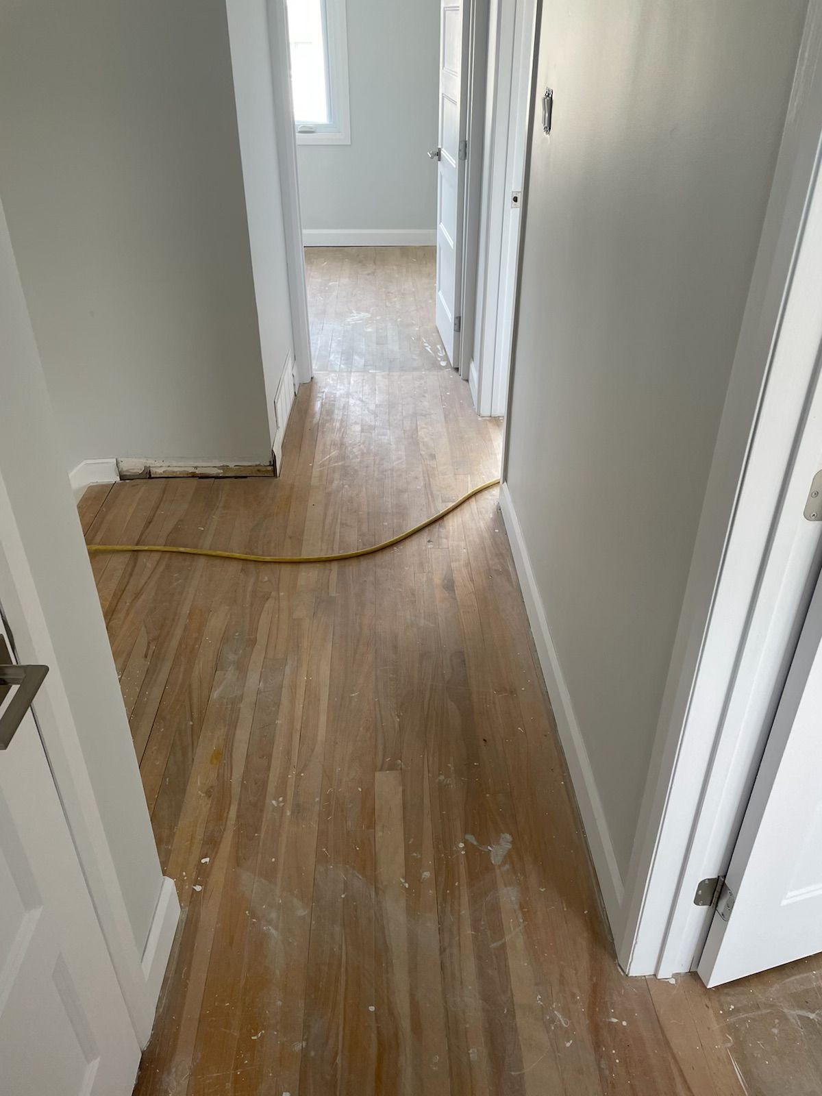 Un couloir avec parquet et murs blancs dans une maison.