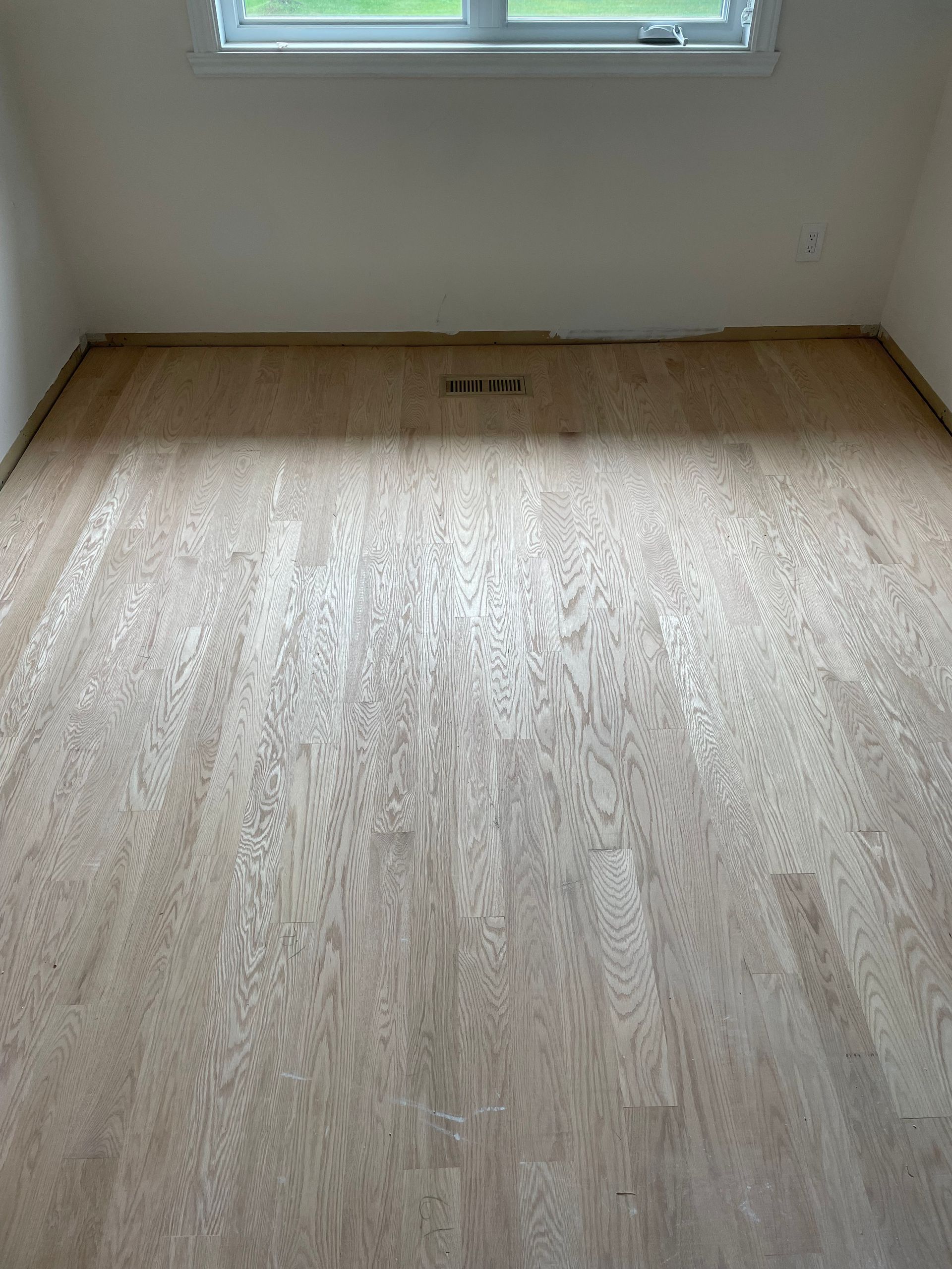 Une pièce avec du parquet et une fenêtre.