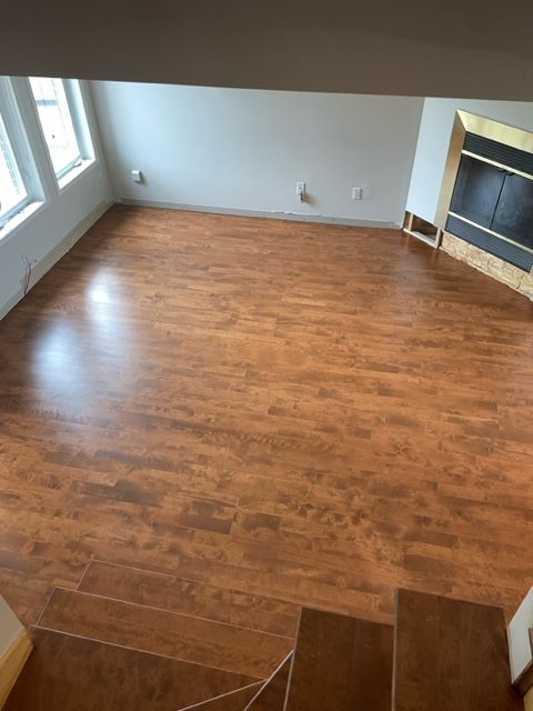 Chambre avec parquet, cheminée et fenêtres. Vue plongeante depuis l'escalier.