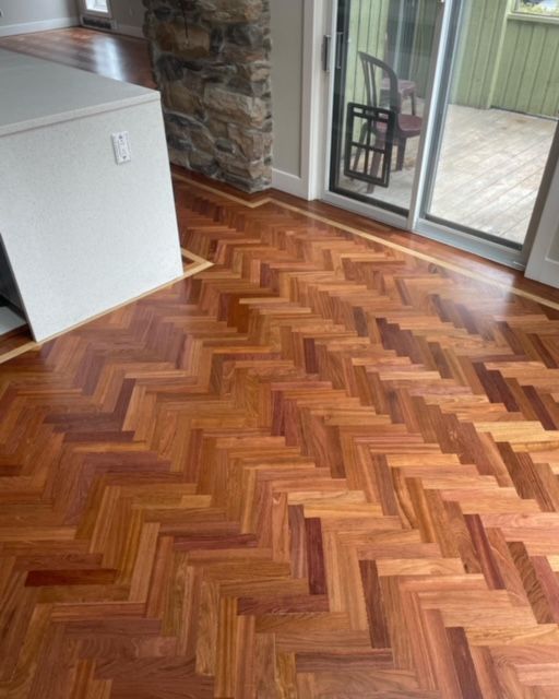 Plancher de bois franc à motif à chevrons avec bordure, à côté d'une armoire blanche et d'une porte vitrée.