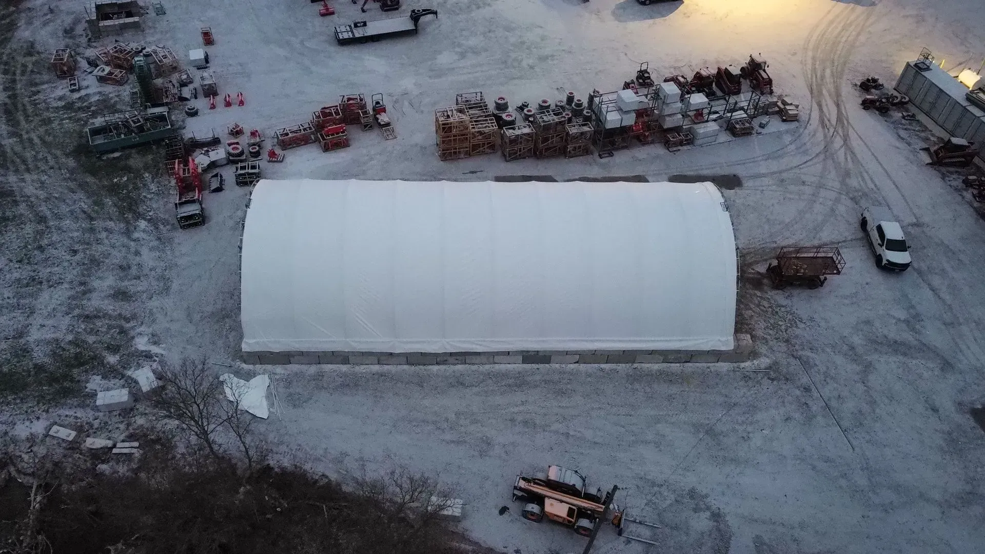 An aerial view of a large white building in the middle of a snowy field.