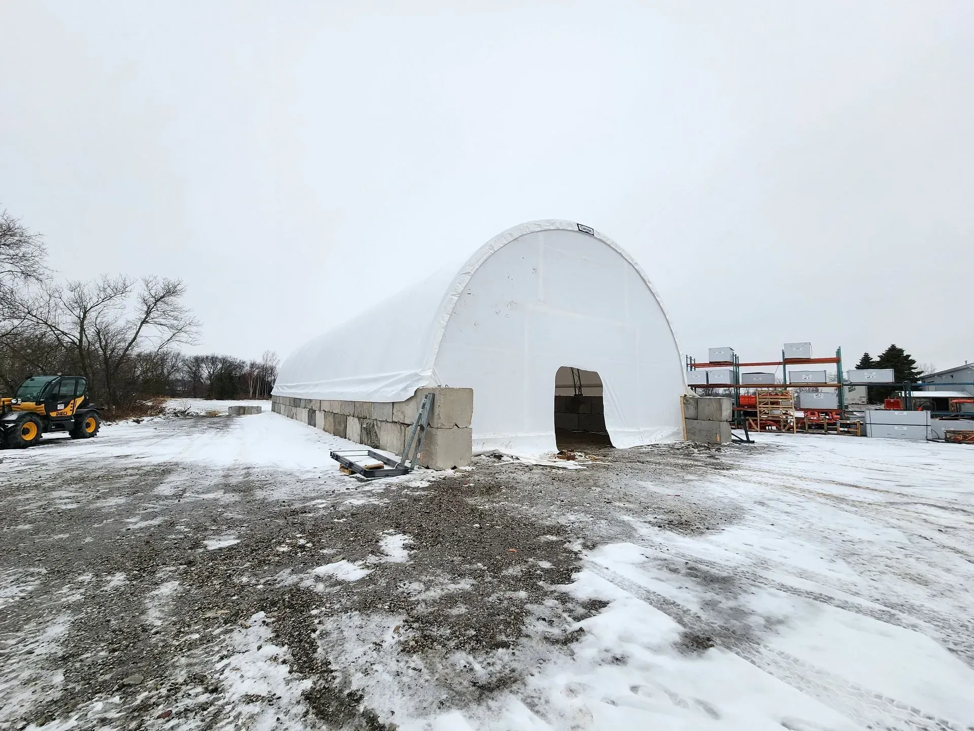 A large white building is sitting in the middle of a snowy field.