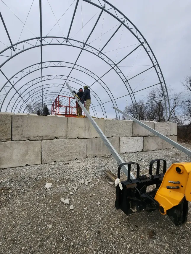 A yellow snow blower is parked in front of a building under construction
