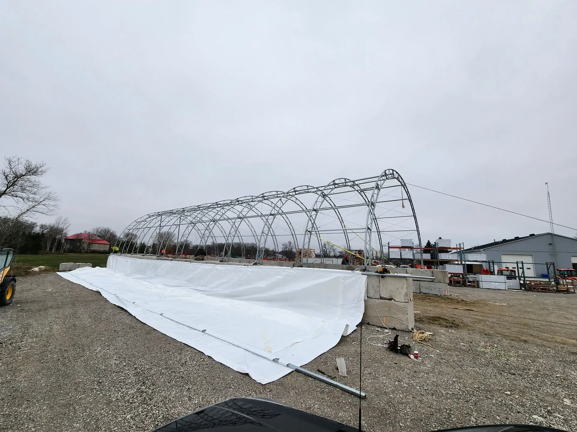 A large tent is being built in a gravel lot.