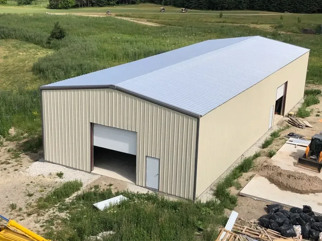 An aerial view of a large metal building in a field.
