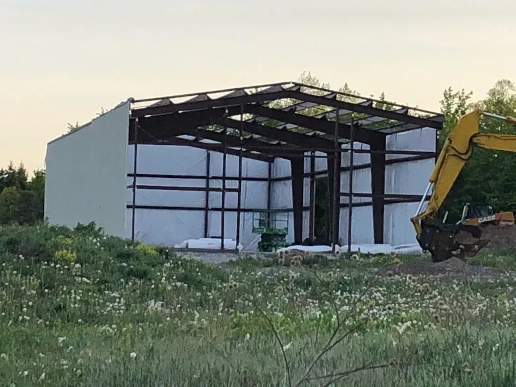A yellow excavator is digging in front of a building under construction.
