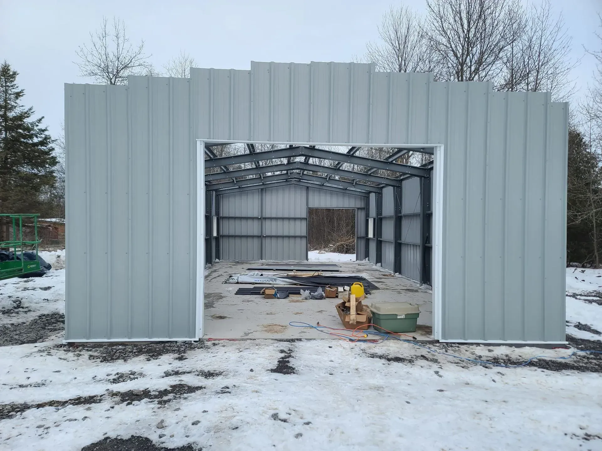 A large metal building is being built in the snow.