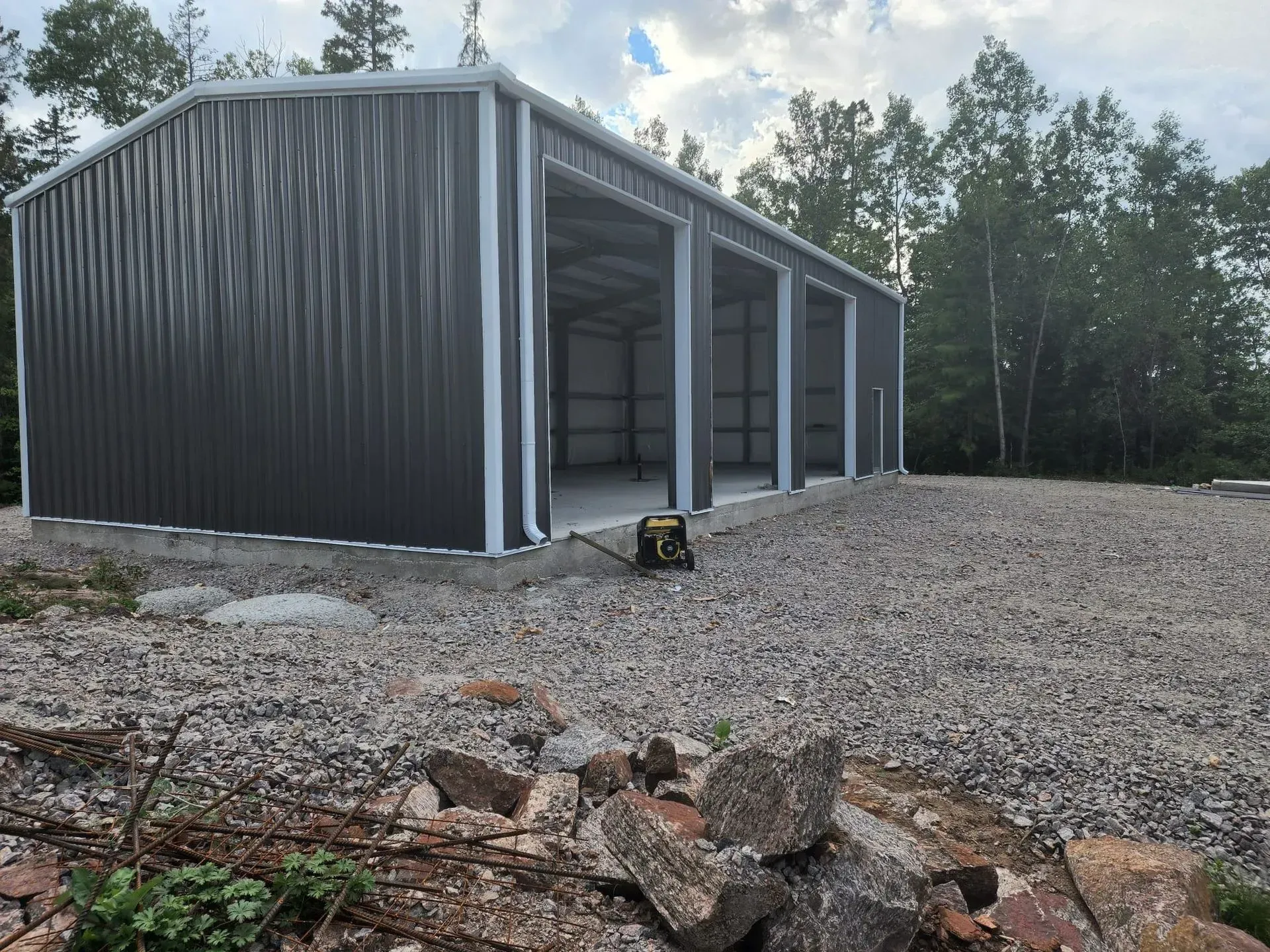 A large metal building is sitting on top of a gravel lot.