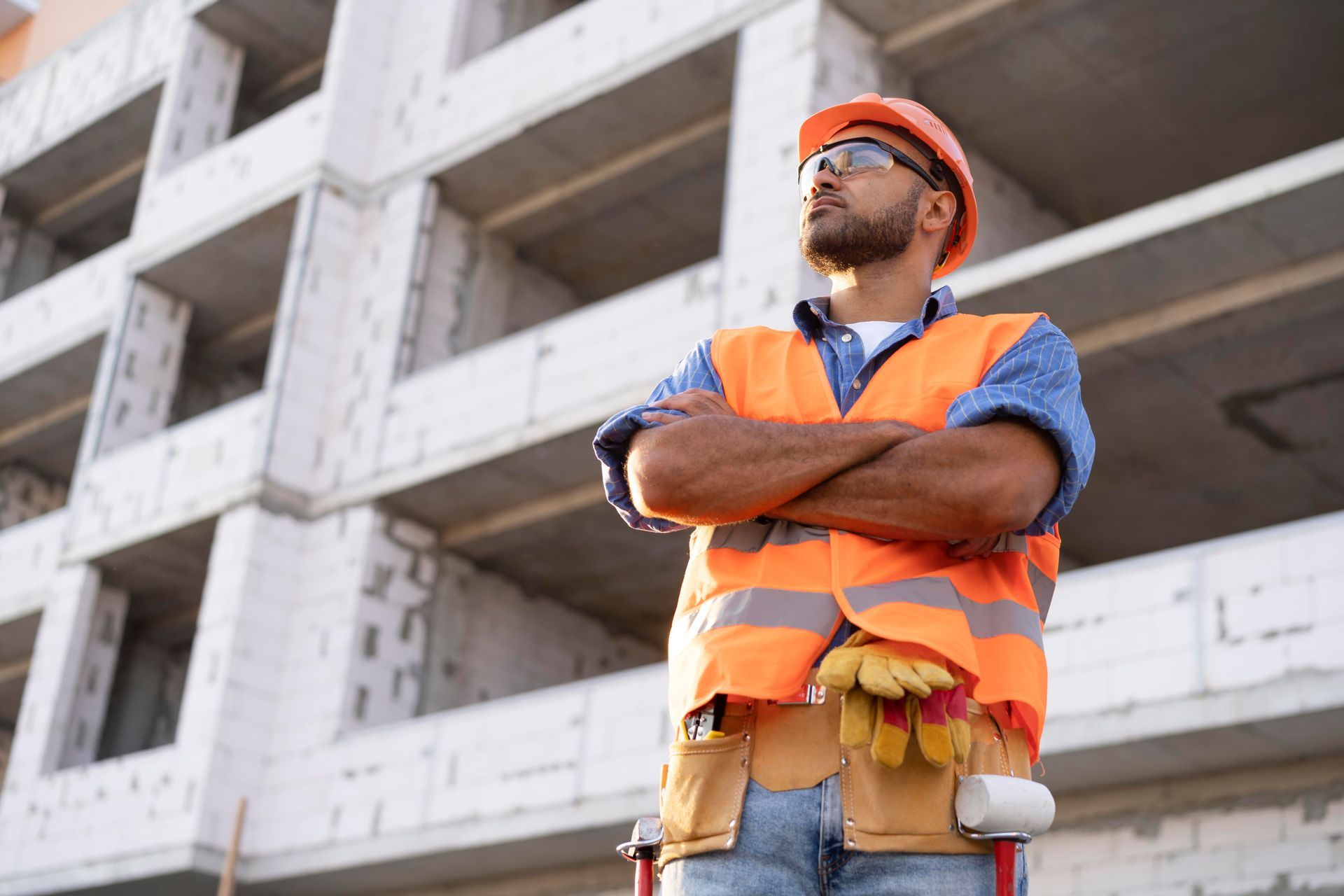 A construction worker is standing in front of a building under construction.