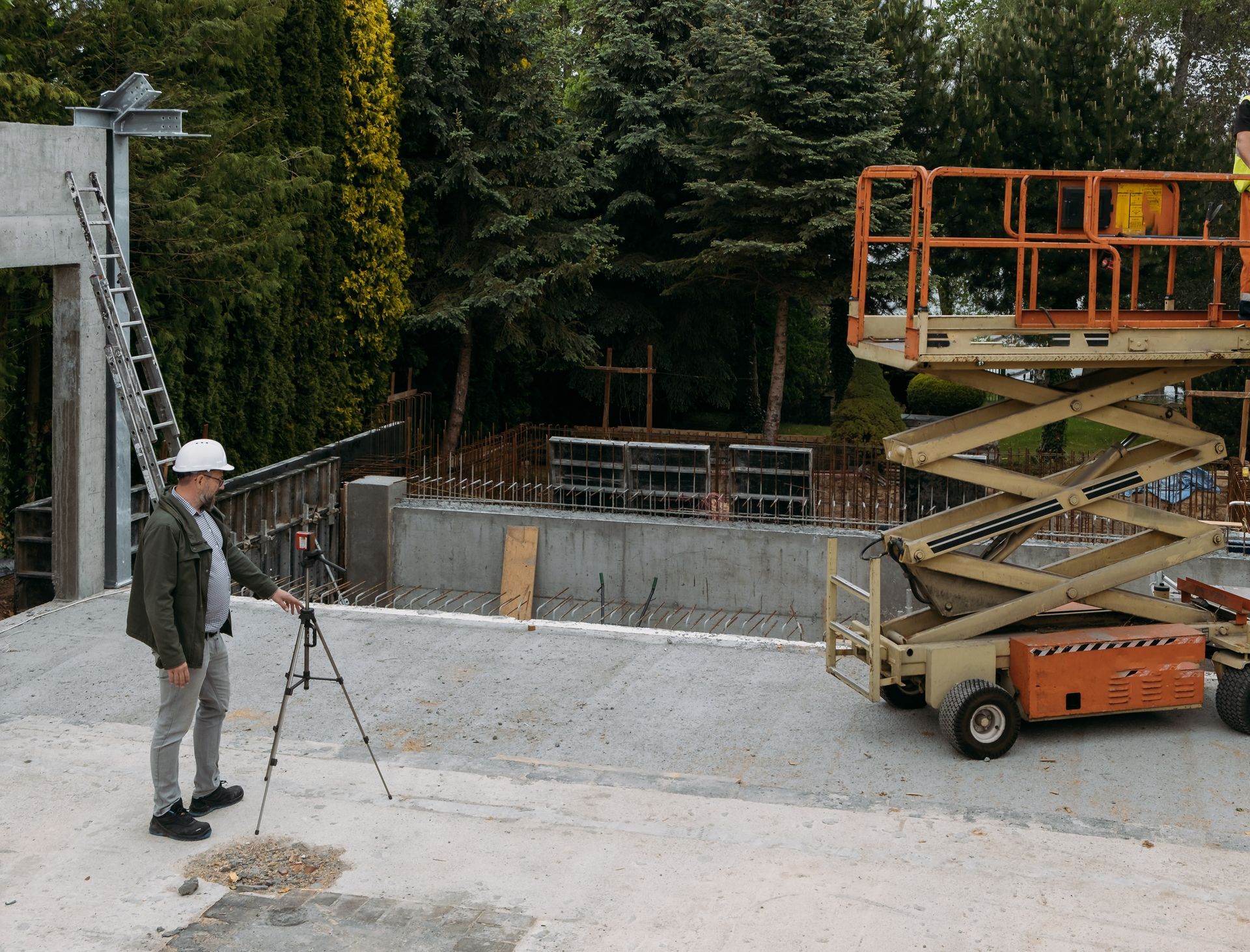 A man in a hard hat is standing in front of a scissor lift