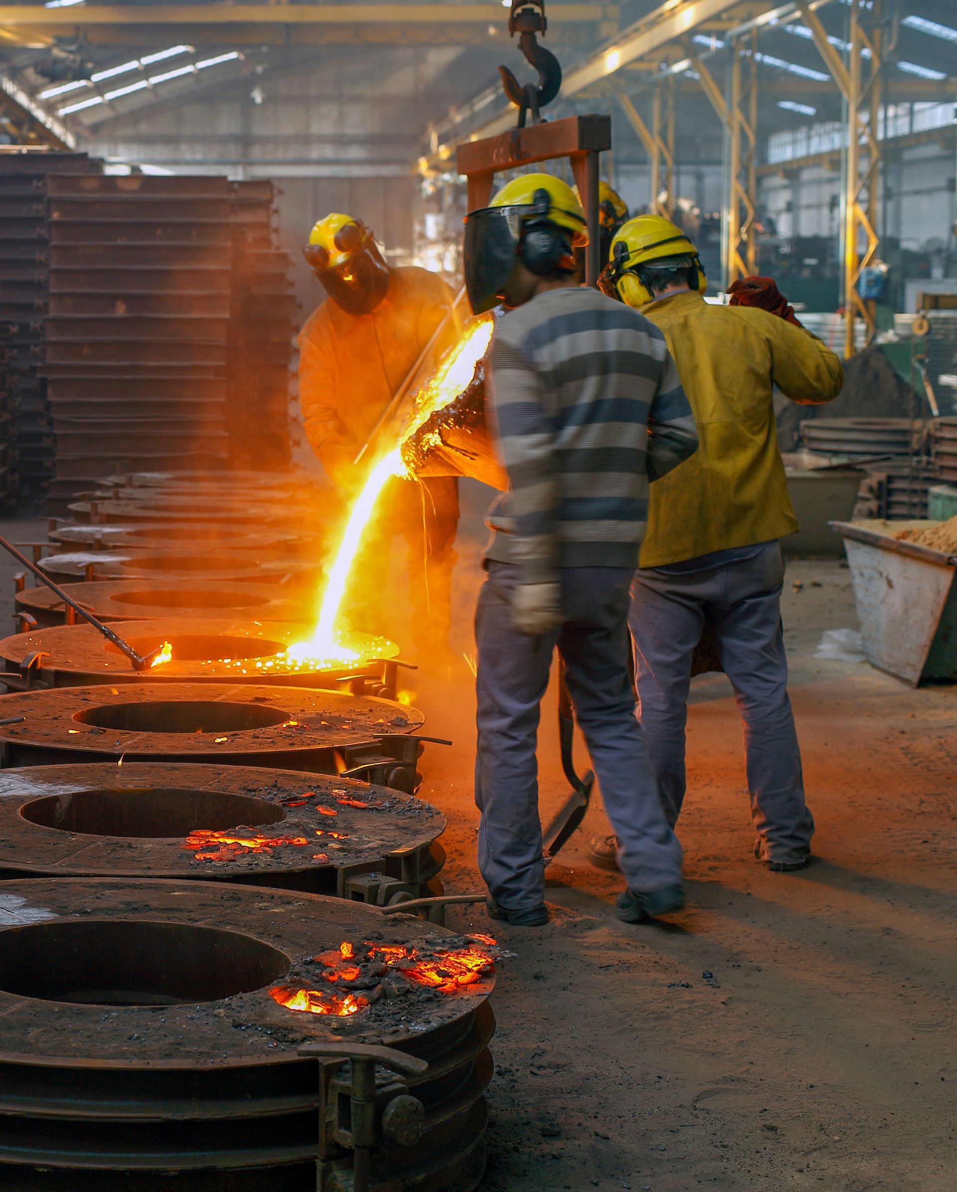 A group of men are working in a factory pouring molten metal