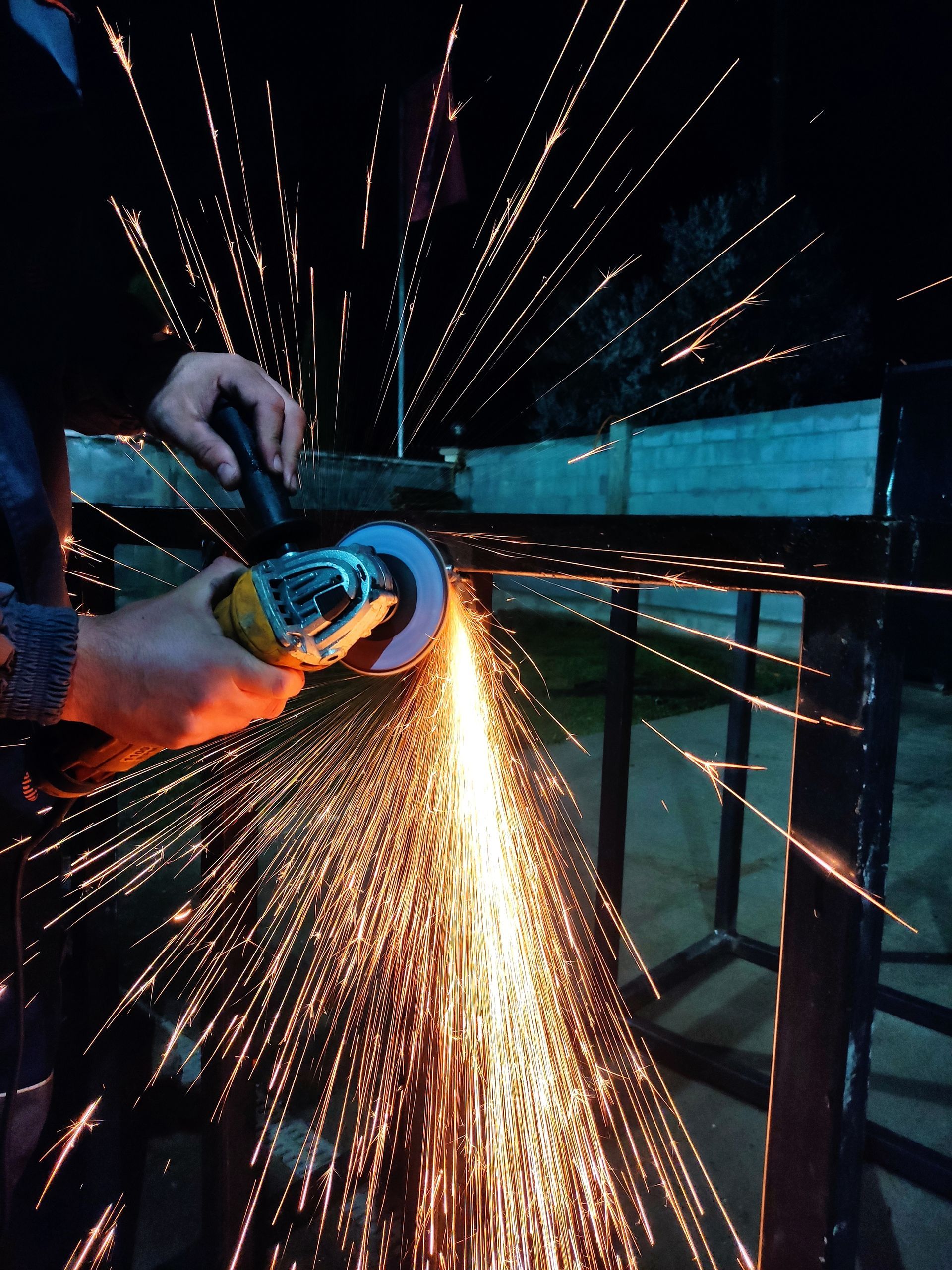 A person is grinding a piece of metal with sparks coming out of it