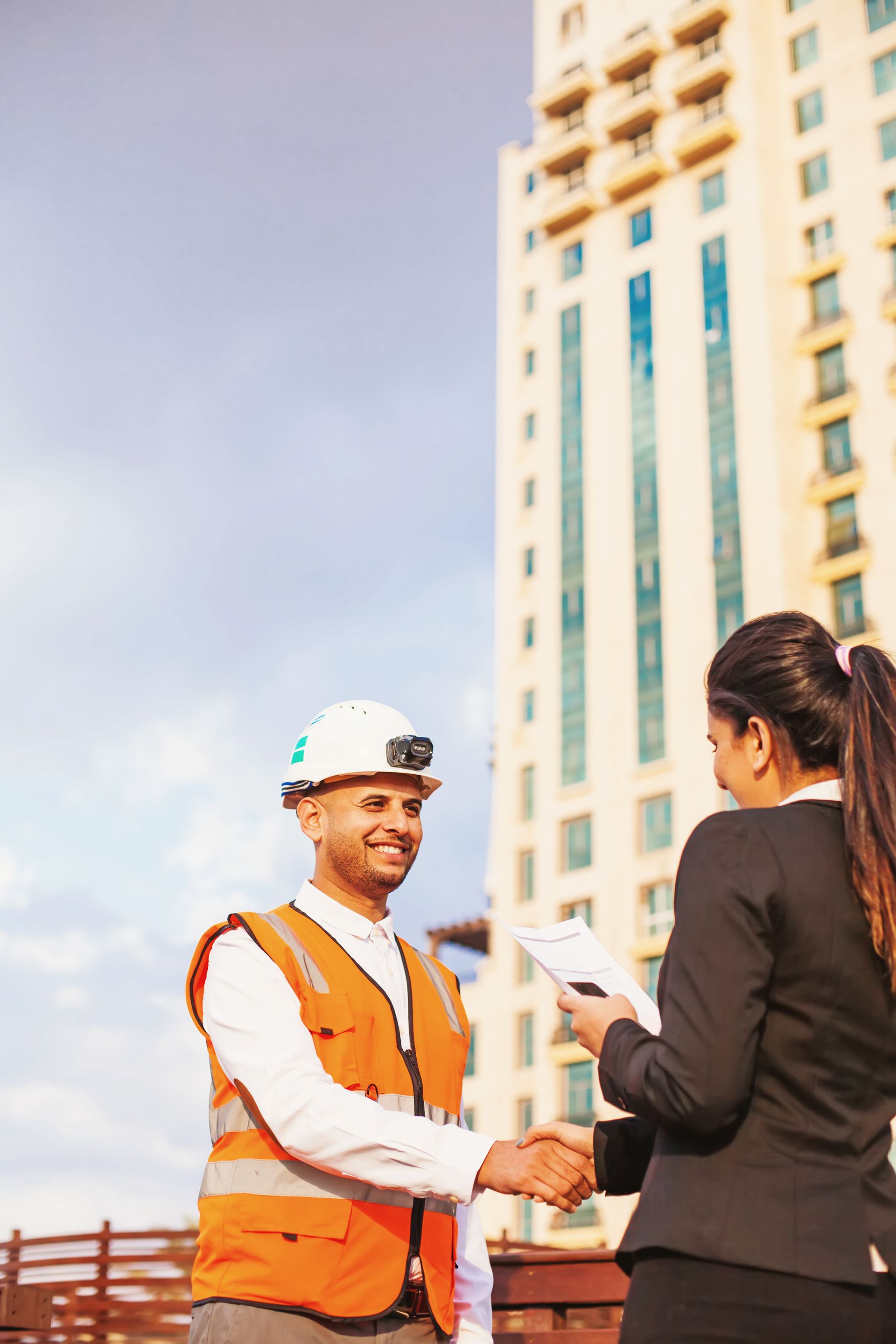 A man and a woman are shaking hands in front of a building.