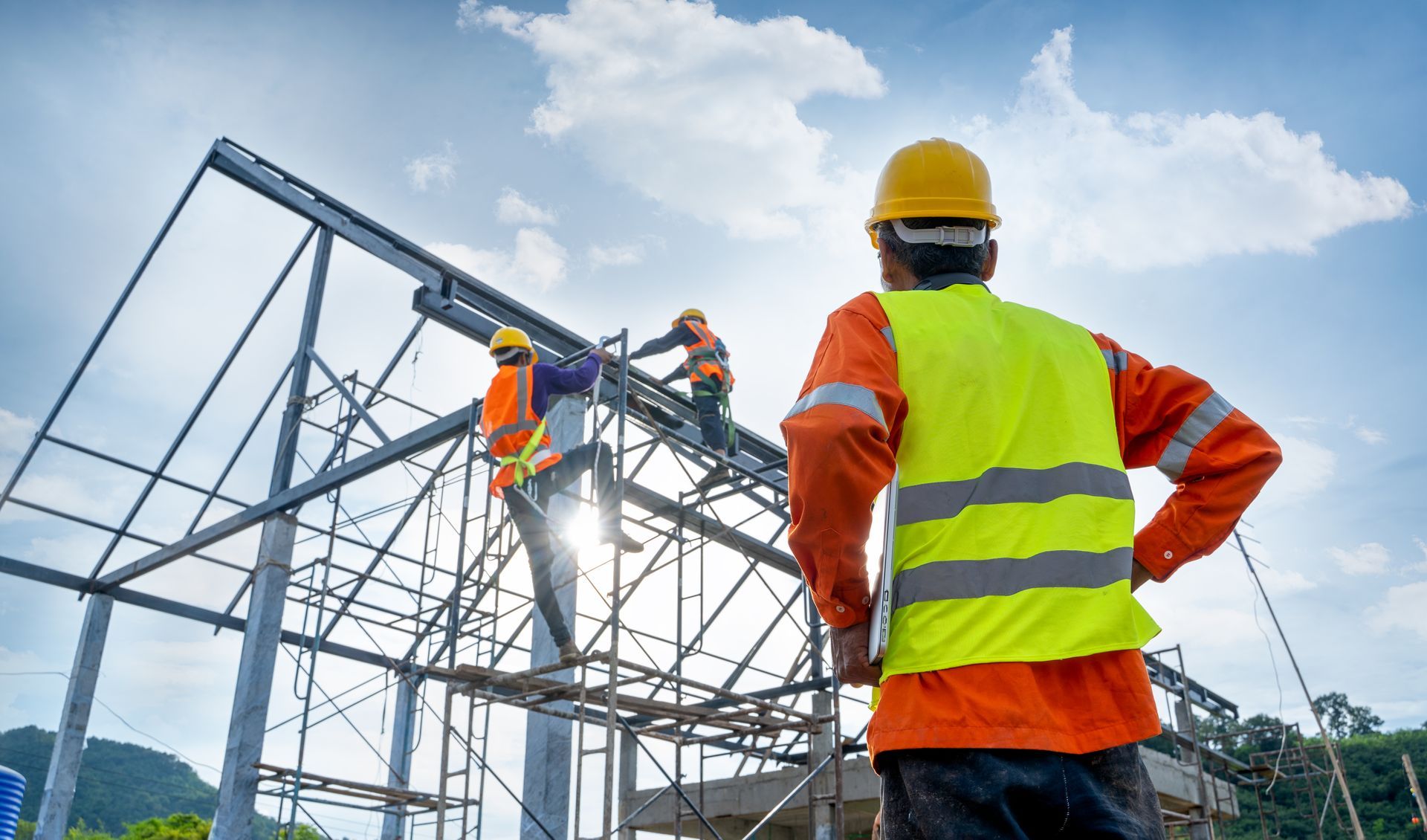 A construction worker is standing in front of a building under construction.