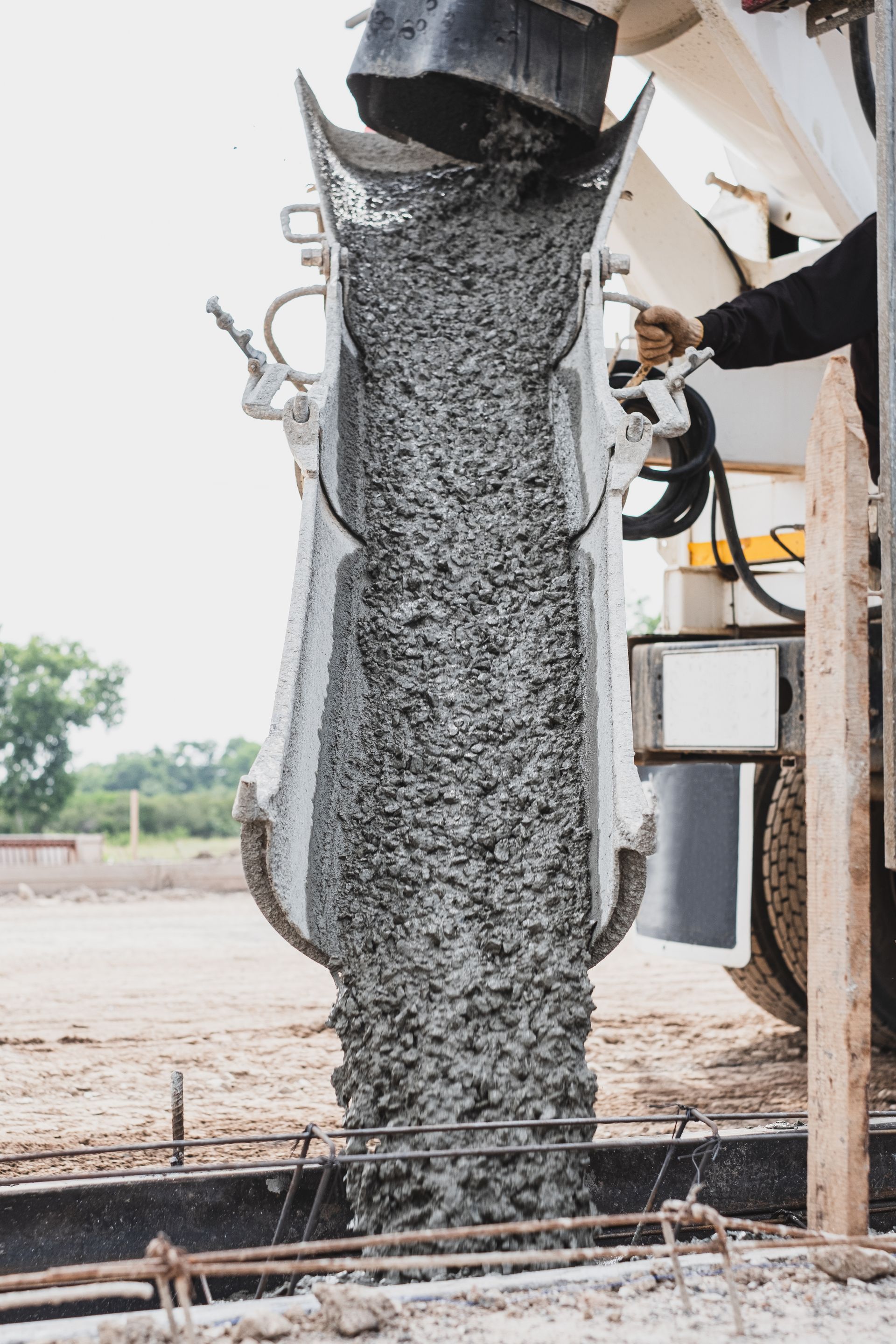 A concrete truck is pouring concrete into a bucket at a construction site.