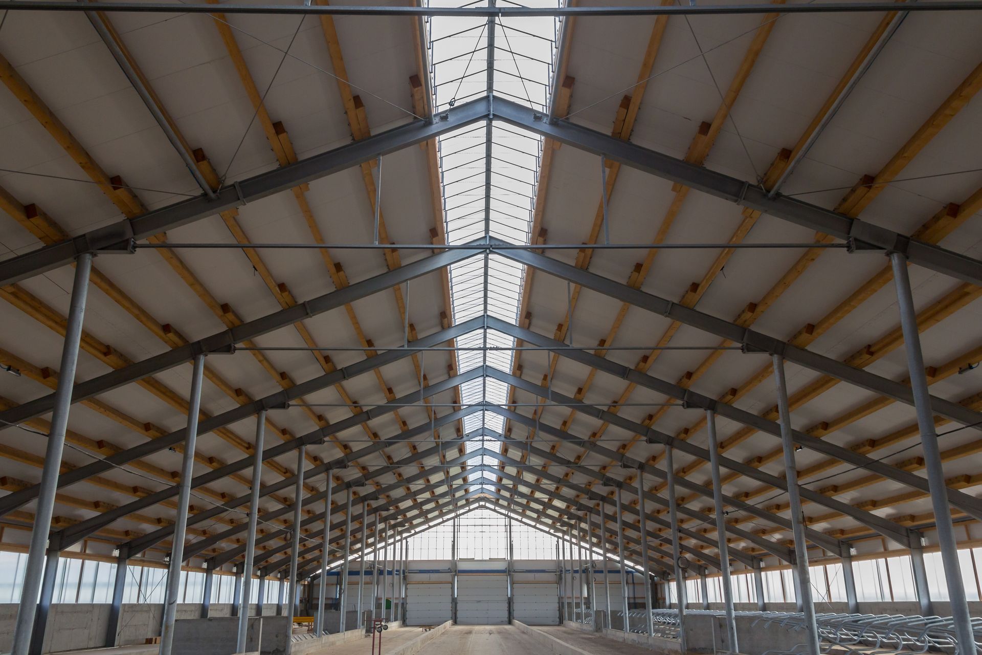 The inside of a large building with a metal frame and wooden beams.