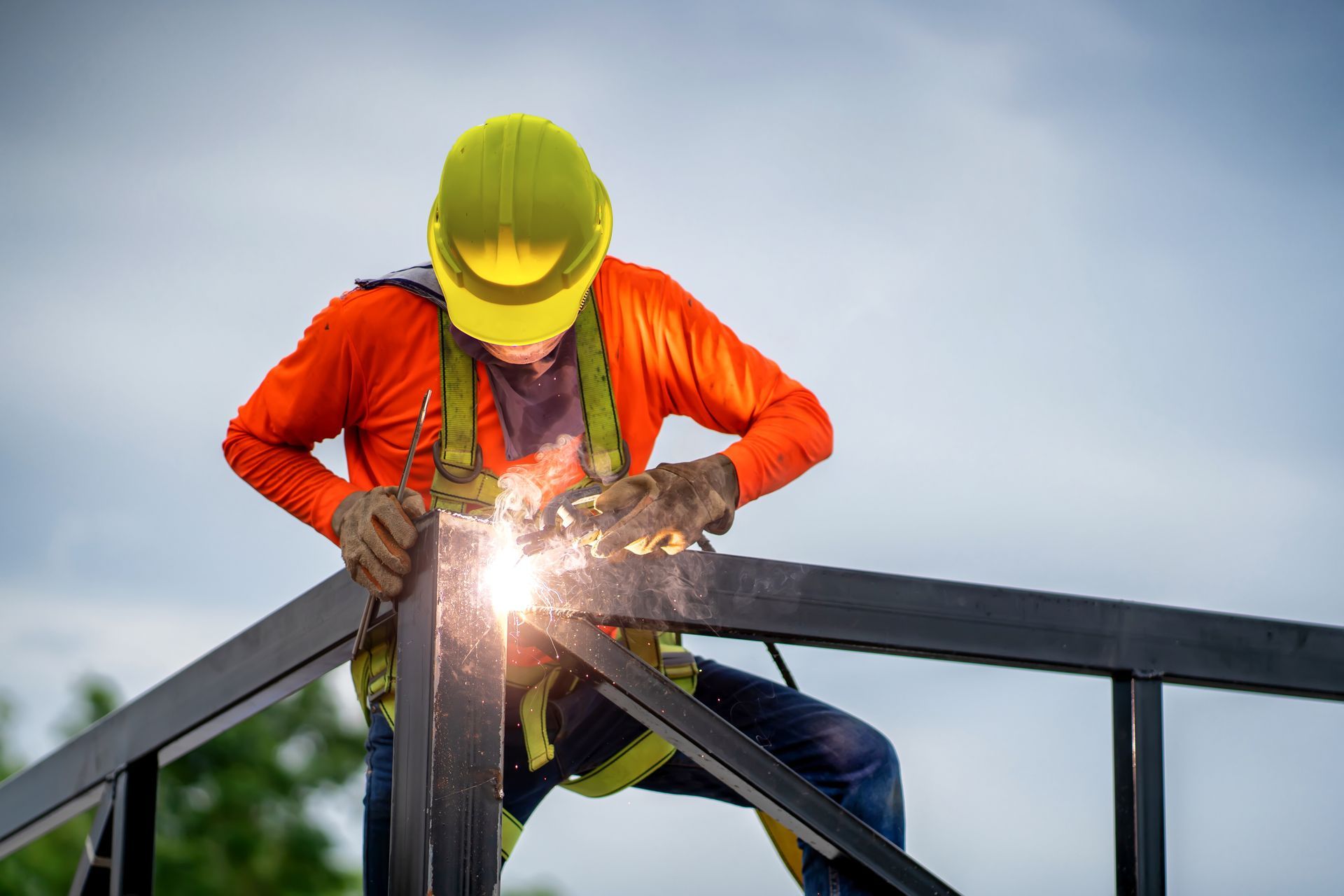 A man is welding a metal structure on top of a building.