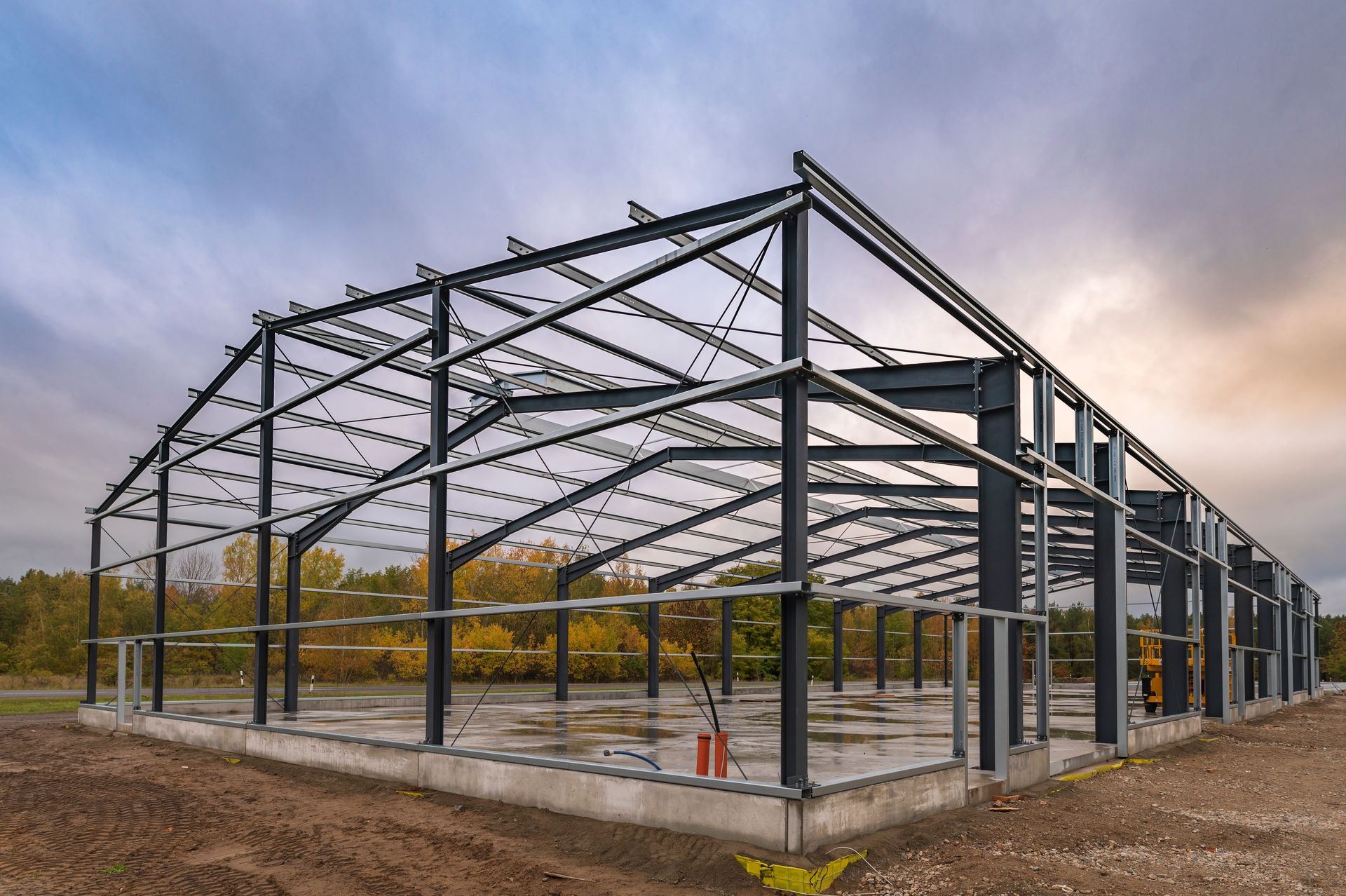 A large metal structure is being built on top of a dirt field.