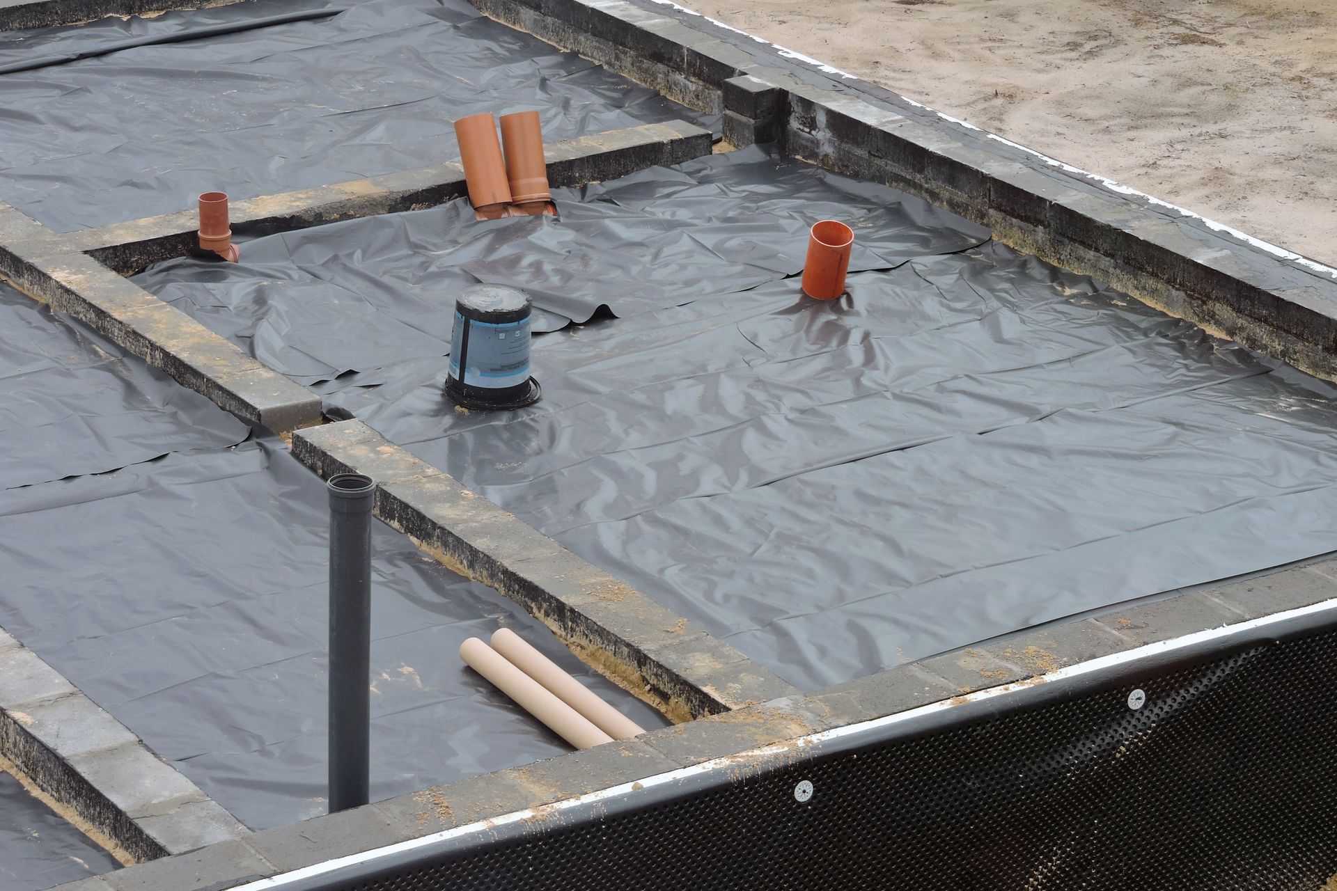 A construction site with a lot of pipes laying on the ground.