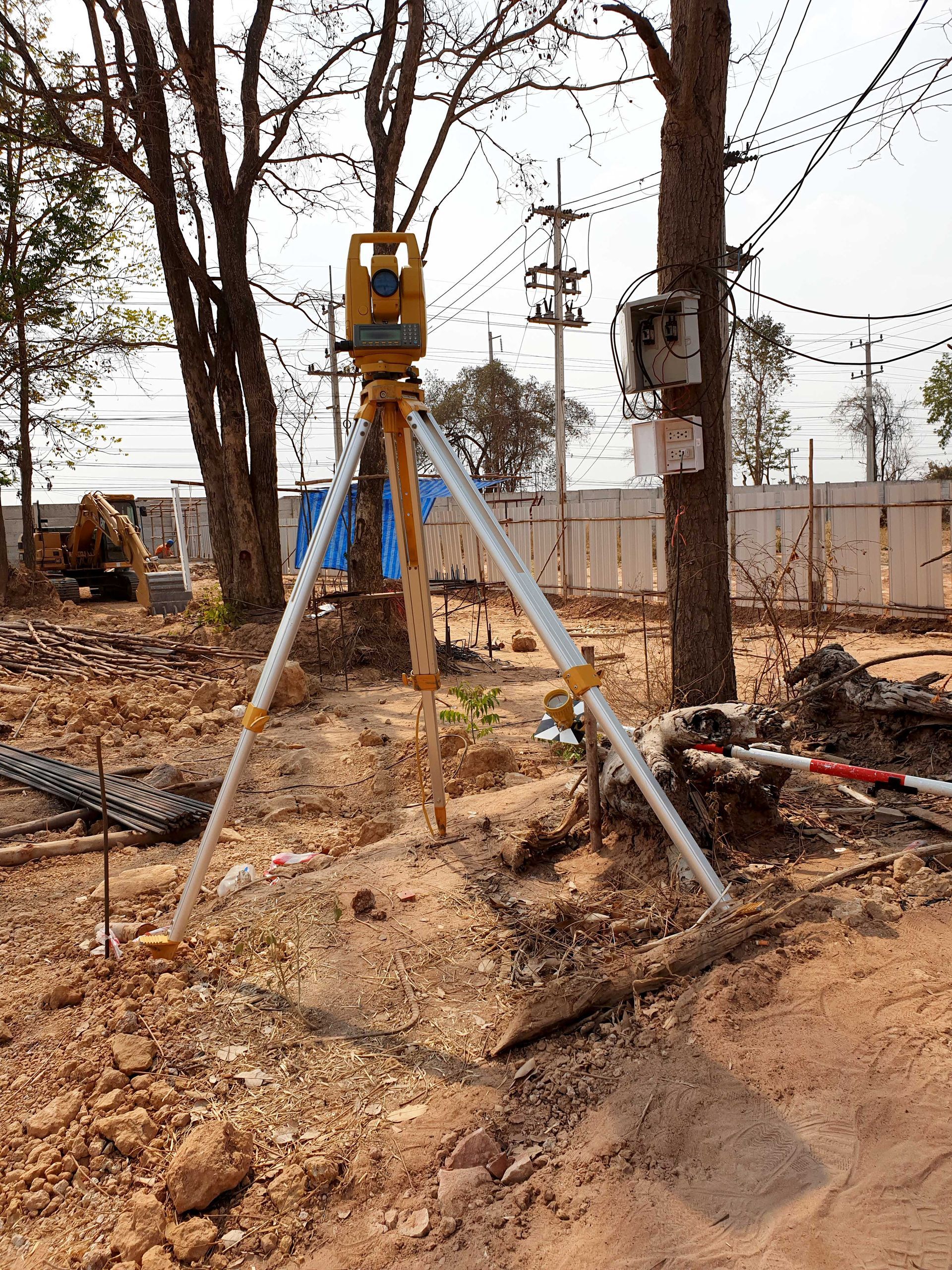 A total station is sitting on top of a pile of dirt in a construction site.