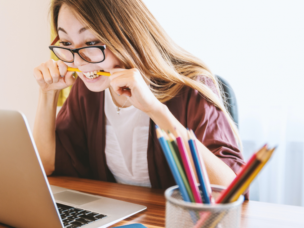 A woman wearing glasses is sitting at a desk using a laptop computer.