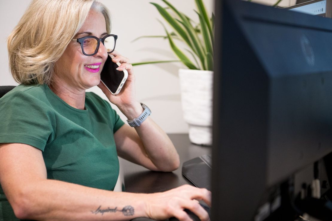 A woman wearing glasses is sitting in front of a dell laptop computer.